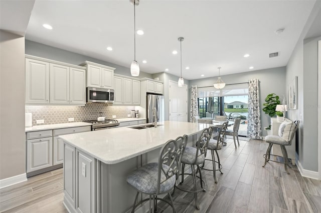 kitchen with a sink, visible vents, appliances with stainless steel finishes, a large island, and tasteful backsplash