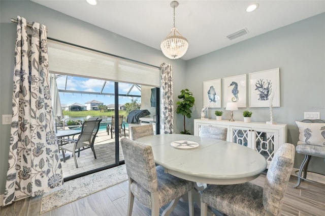 dining area featuring a notable chandelier, wood finish floors, visible vents, and recessed lighting