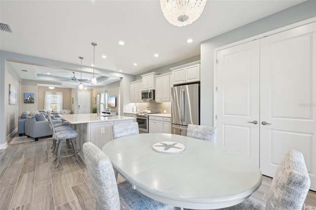 dining space featuring baseboards, light wood finished floors, a notable chandelier, and recessed lighting