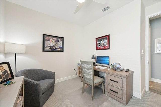 office area with visible vents, baseboards, a ceiling fan, and light colored carpet