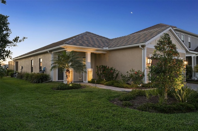 view of front facade featuring a garage, a front yard, a tile roof, and stucco siding