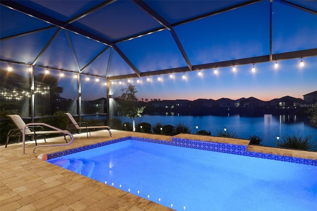 pool with glass enclosure, a patio area, and a water view