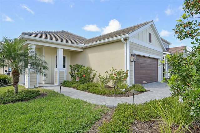 view of front of house with a garage, decorative driveway, board and batten siding, and stucco siding