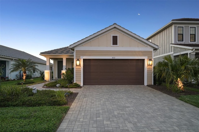 view of front of home with an attached garage, decorative driveway, and board and batten siding