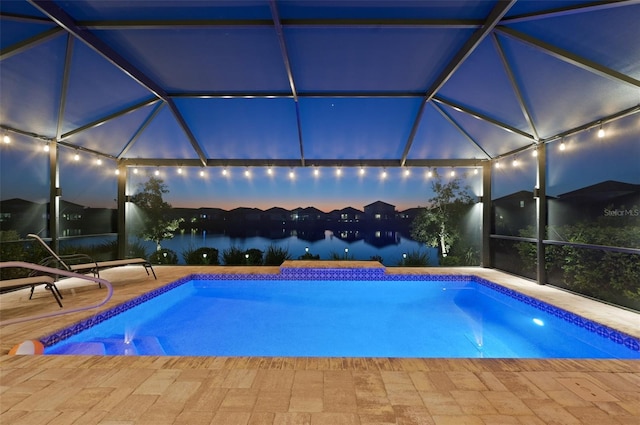 pool featuring glass enclosure, a patio area, and a water view