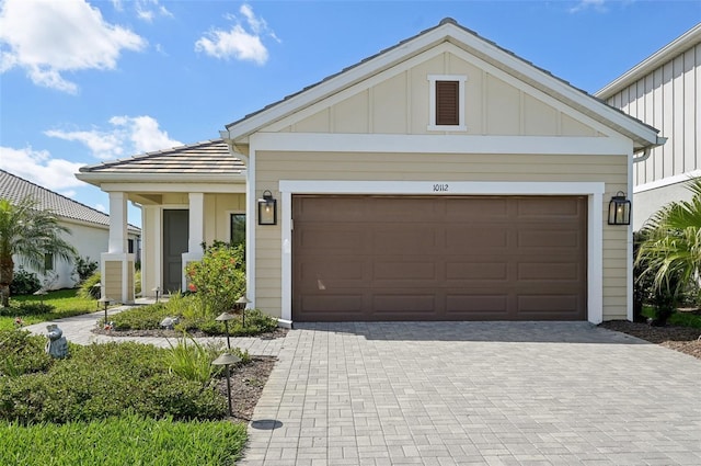 view of front of house with board and batten siding, decorative driveway, and an attached garage