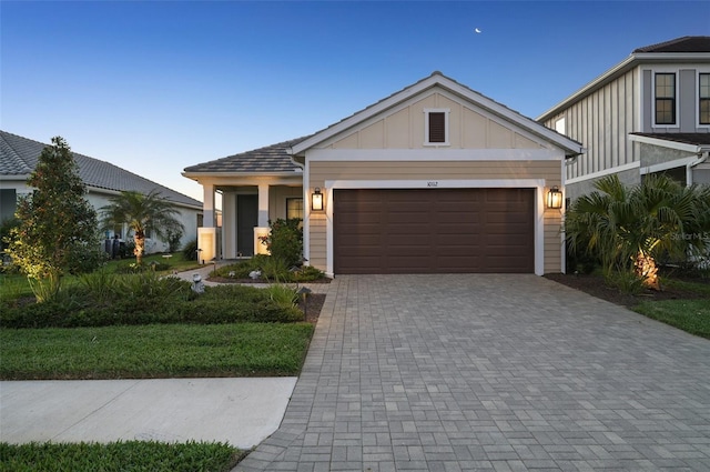 craftsman inspired home featuring board and batten siding, driveway, an attached garage, and a front yard