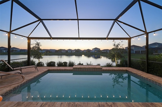 pool at dusk featuring a water view, glass enclosure, an outdoor pool, and a patio
