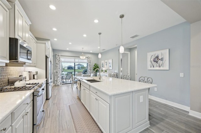 kitchen featuring stainless steel appliances, a sink, white cabinets, backsplash, and recessed lighting