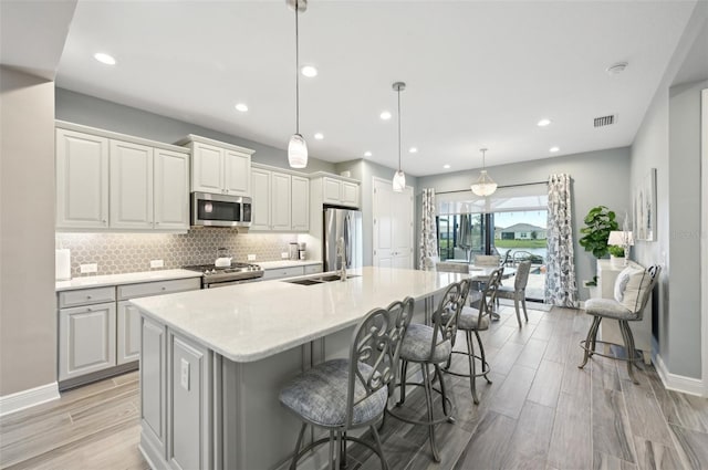 kitchen with appliances with stainless steel finishes, a large island, decorative backsplash, light countertops, and recessed lighting