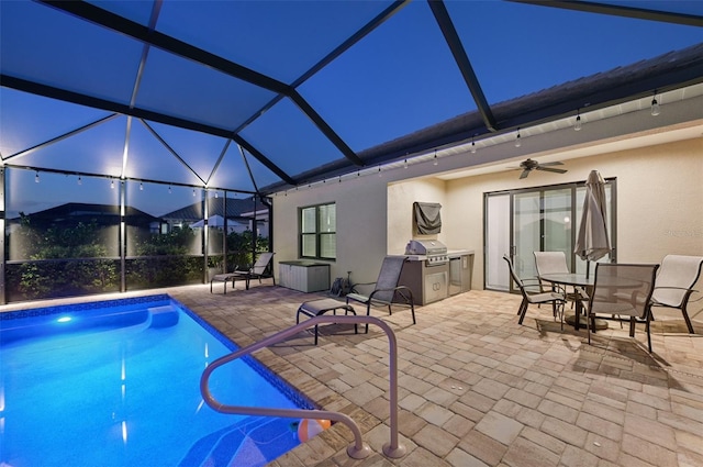 pool at night featuring a ceiling fan, a patio area, an outdoor pool, grilling area, and a lanai