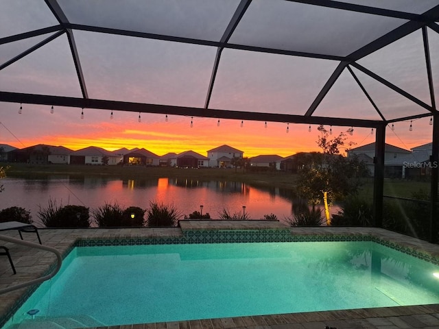 outdoor pool featuring a water view, glass enclosure, a residential view, and a patio area