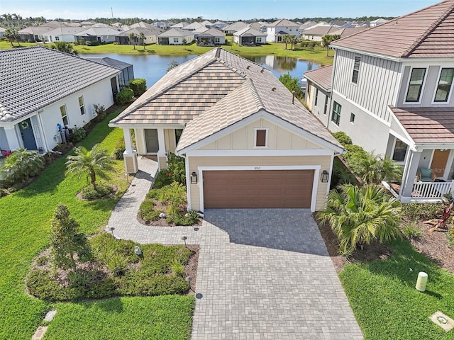 view of front of property featuring board and batten siding, a residential view, a water view, decorative driveway, and an attached garage