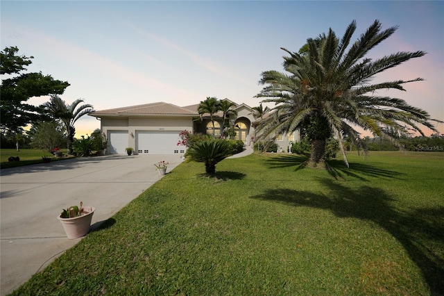 view of front of house with a garage, a front lawn, concrete driveway, and stucco siding