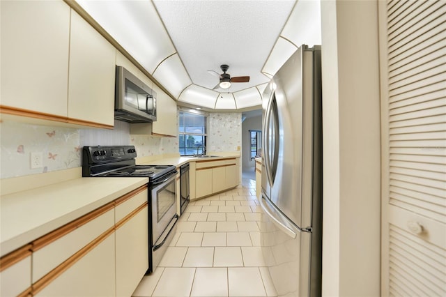 kitchen featuring light tile patterned floors, light countertops, appliances with stainless steel finishes, a ceiling fan, and a sink