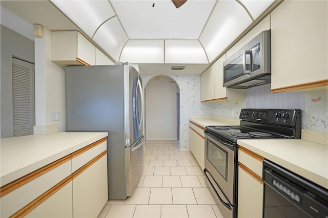 kitchen with arched walkways, stainless steel appliances, light countertops, and white cabinetry