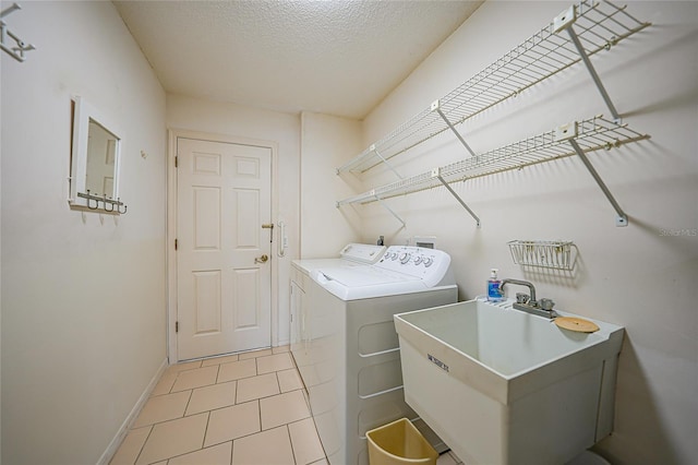 washroom with laundry area, baseboards, independent washer and dryer, a textured ceiling, and a sink