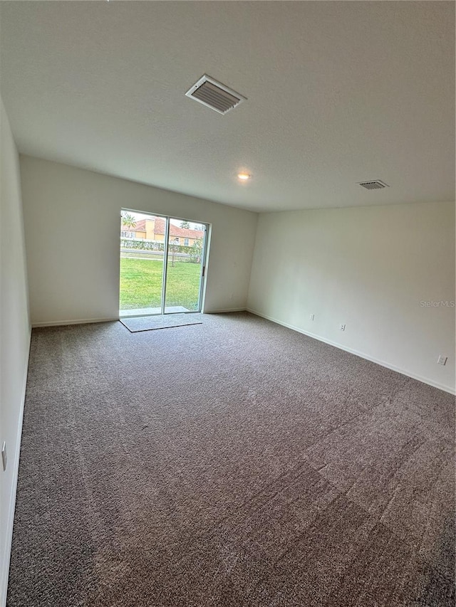 empty room featuring a textured ceiling, carpet floors, visible vents, and baseboards