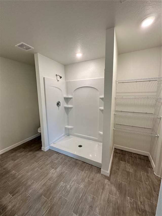 bathroom featuring a textured ceiling, wood finish floors, and visible vents