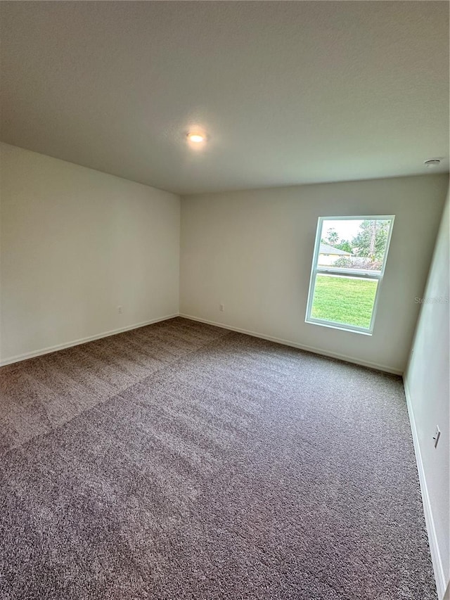 spare room featuring carpet and baseboards