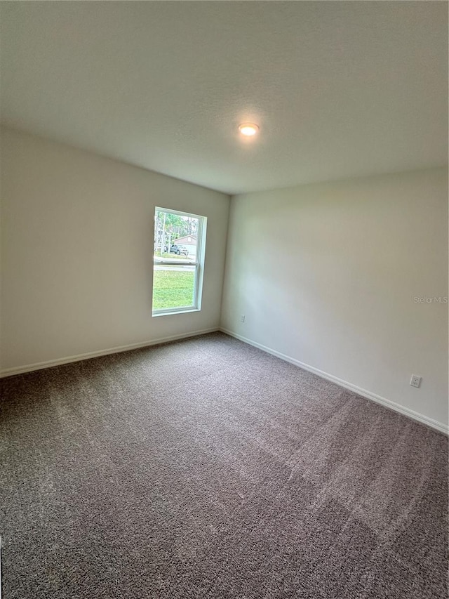 carpeted spare room featuring a textured ceiling and baseboards