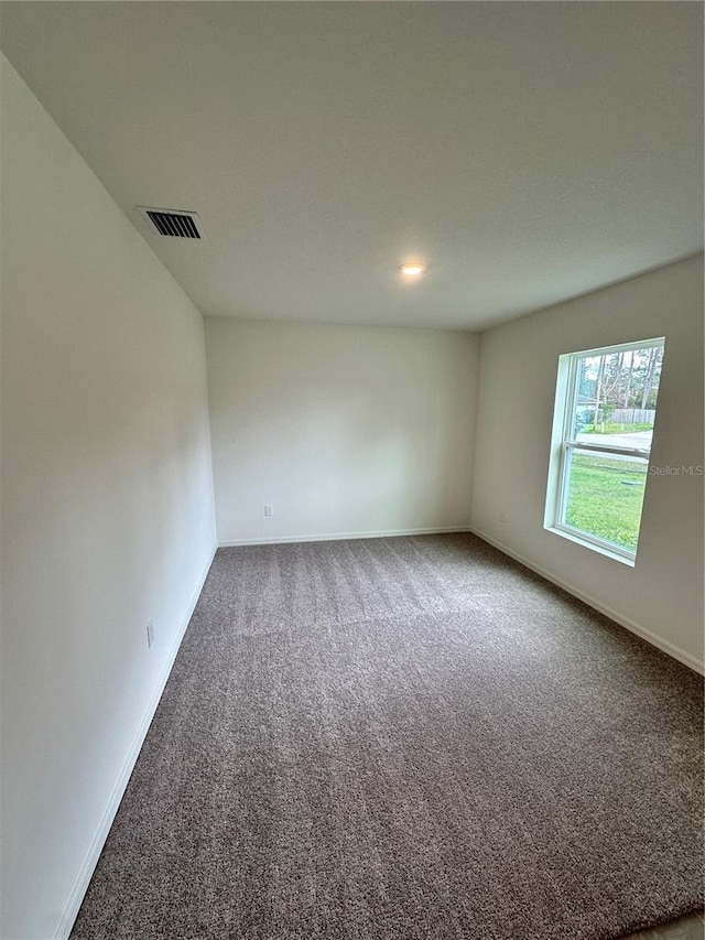 spare room with baseboards, visible vents, and carpet flooring