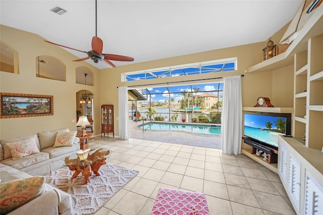 living room featuring a ceiling fan, arched walkways, light tile patterned flooring, and visible vents