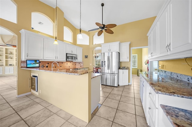 kitchen featuring a peninsula, white cabinetry, stainless steel appliances, and light tile patterned flooring