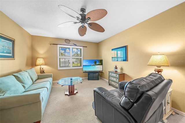 living area featuring a ceiling fan, light colored carpet, and baseboards