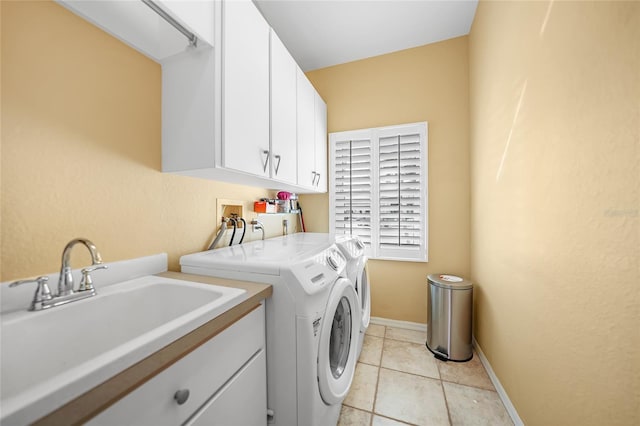 laundry area featuring cabinet space, light tile patterned floors, baseboards, washer and clothes dryer, and a sink