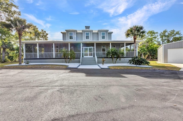 view of front of house featuring a sunroom, a porch, and a garage