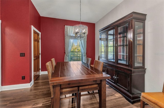 dining space with an inviting chandelier, dark wood-type flooring, and baseboards
