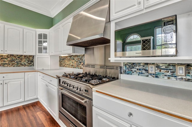 kitchen featuring wall chimney range hood, white cabinetry, crown molding, and high end stainless steel range