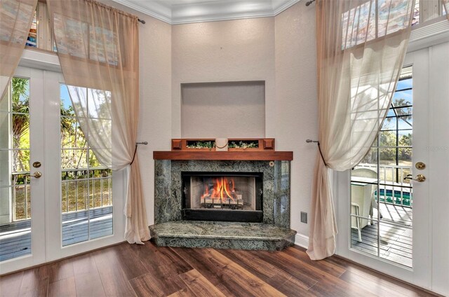interior details featuring french doors, ornamental molding, a lit fireplace, and wood finished floors