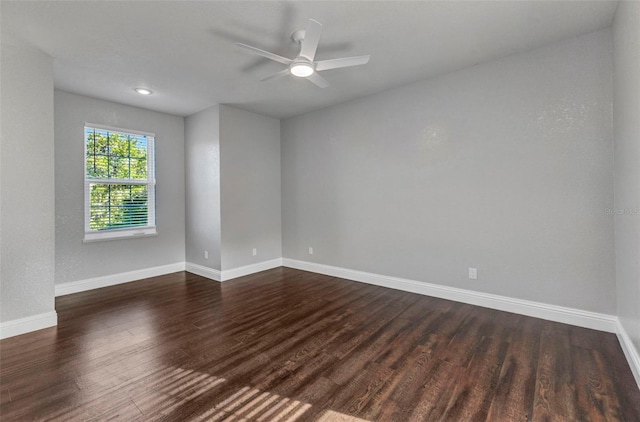 spare room featuring baseboards, dark wood-style flooring, and ceiling fan