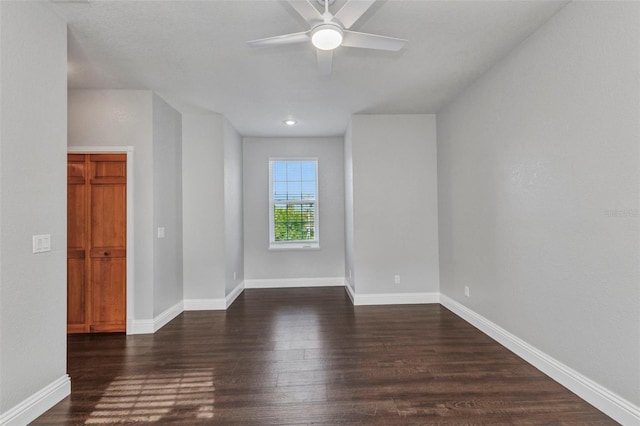 spare room featuring baseboards, dark wood-style floors, and a ceiling fan