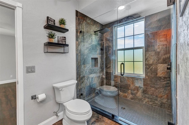full bath with a stall shower, baseboards, and toilet