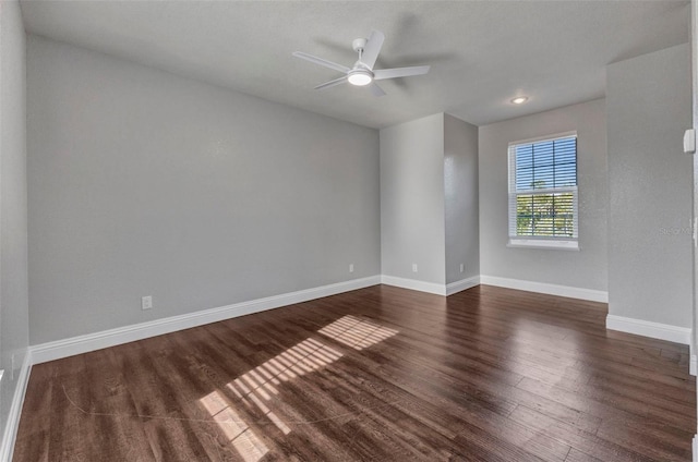 empty room featuring dark wood-style floors, baseboards, and ceiling fan