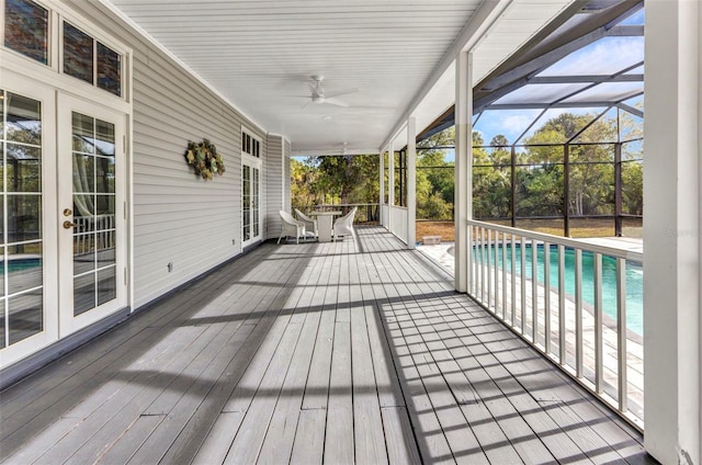 deck with french doors, an outdoor pool, glass enclosure, and ceiling fan