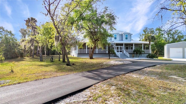 view of front of house featuring aphalt driveway, an outbuilding, a sunroom, and a front lawn