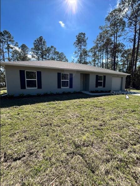 single story home with a garage, a front yard, and stucco siding