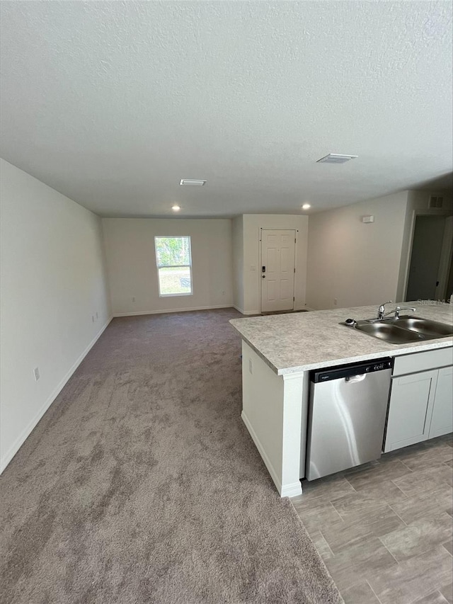 kitchen featuring open floor plan, light countertops, stainless steel dishwasher, and a sink