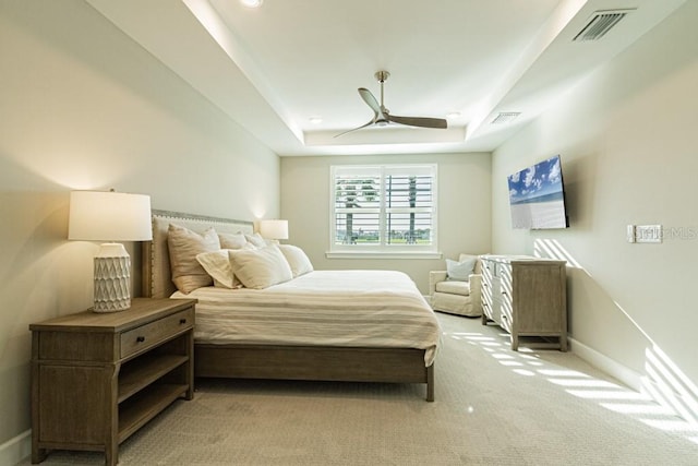 bedroom with baseboards, a tray ceiling, visible vents, and light colored carpet