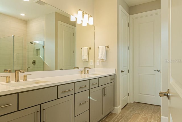 bathroom with wood finish floors, visible vents, a sink, and a shower stall