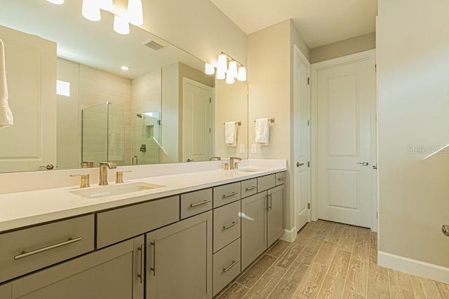 full bath featuring a shower stall, baseboards, a sink, and wood tiled floor