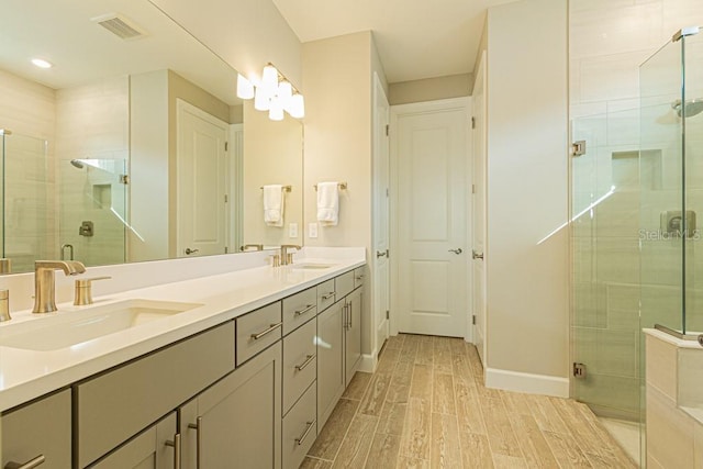 full bath with a stall shower, wood tiled floor, visible vents, and a sink