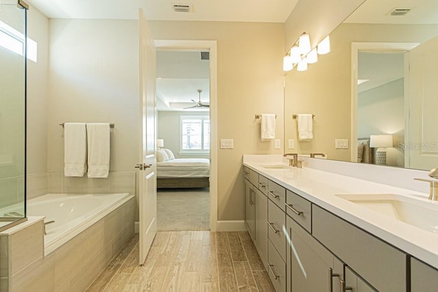 ensuite bathroom with ensuite bath, visible vents, a sink, and wood finished floors