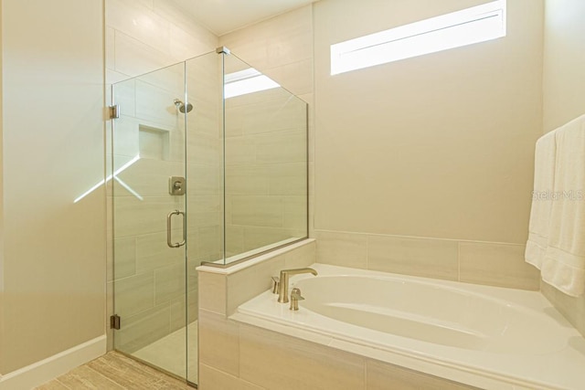 bathroom with a garden tub, a shower stall, and baseboards