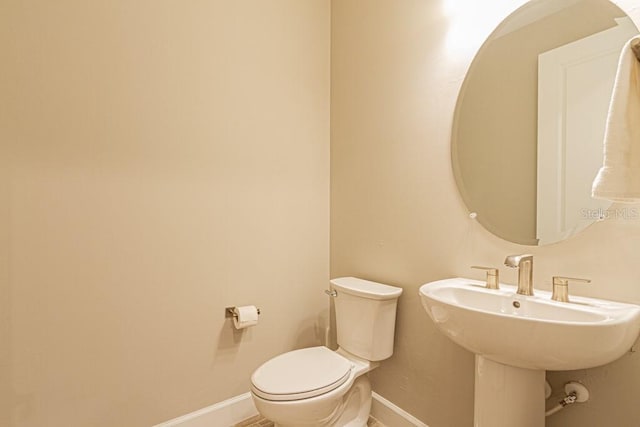 bathroom featuring a sink, toilet, and baseboards