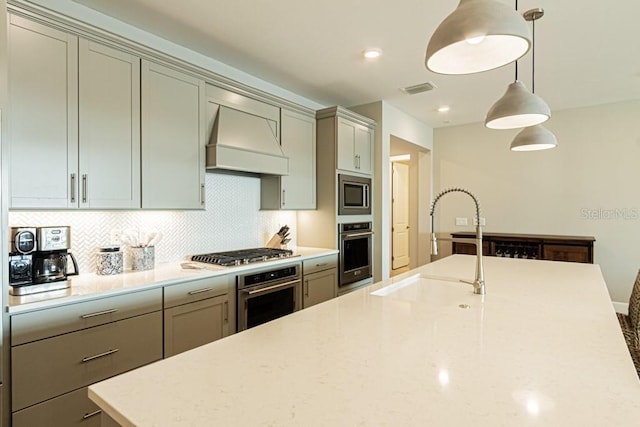 kitchen featuring appliances with stainless steel finishes, custom exhaust hood, decorative light fixtures, and light stone countertops